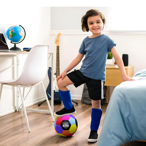 Blue t-shirt and black athletic shorts worn by a child, posing with a colorful soccer ball in a cozy room.