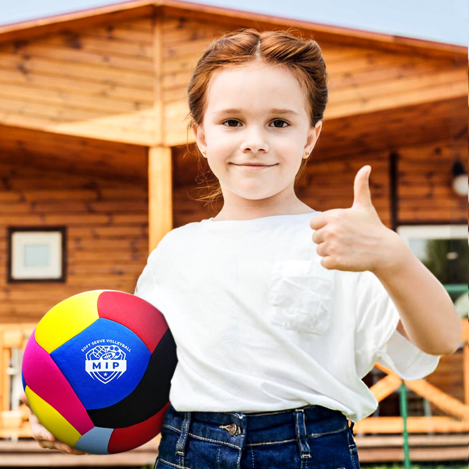 Colorful volleyball held by a girl in a white t-shirt, with a wooden cabin in the background.