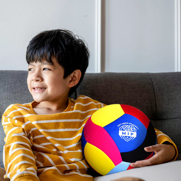 Multi-colored volleyball featuring "MIP" logo, held by a smiling boy in a striped yellow and white shirt.
